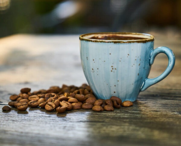 Decaf blend coffee in a cup with coffee beans surrounding