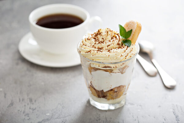 Tiramisu flavored coffee in a cup next to tiramisu dessert